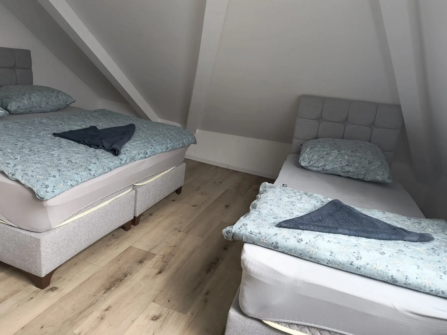 Dachzimmer mit Doppelbett und Einzelbett unter der Dachschräge